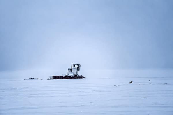 A stranded boat frozen in the vast white expanse of the frozen sea