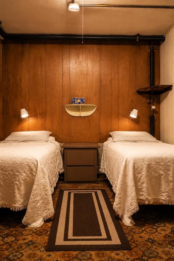 A twin-bed guest room with wood paneling at Waldo Arms