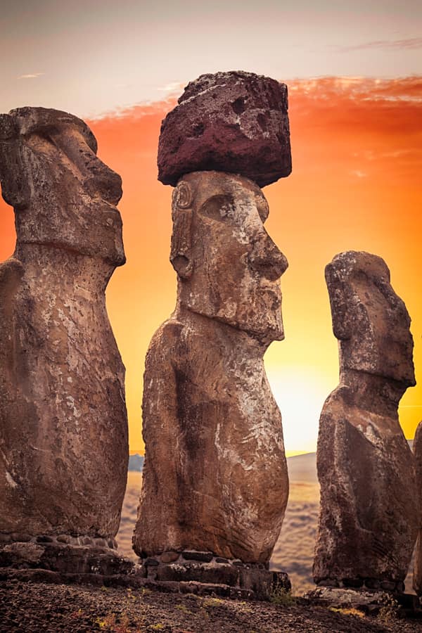 Moai with topknots lit by the low sun against a blue sky