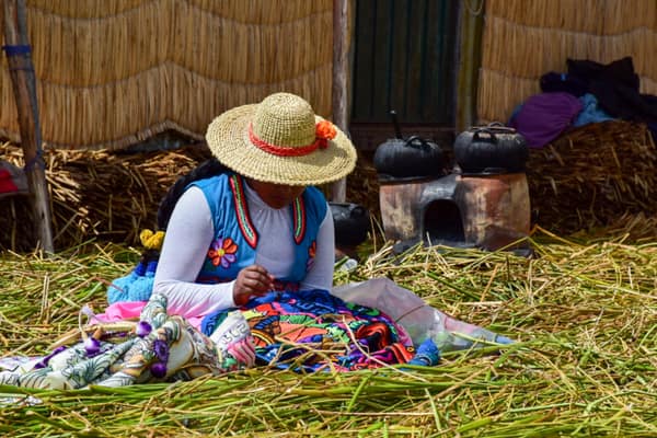 A woman sewing artisanal textiles on a floating island