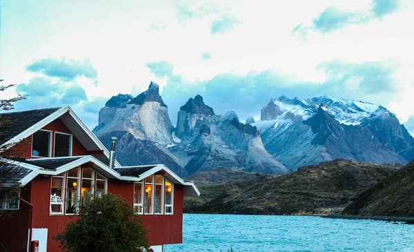 A red lakeside lodge below the Cuernos del Paine at dusk