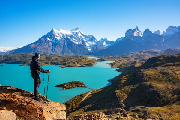 A hiker on a rocky overlook above Lago Pehoé and the massif