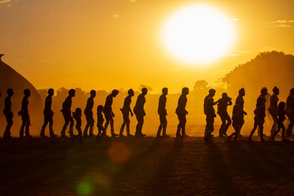 Community members walking in line at sunset in the Xingu village