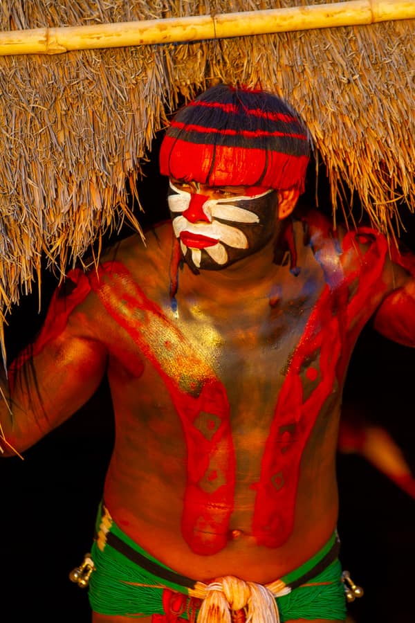 A dancer in red body paint and a feather headdress