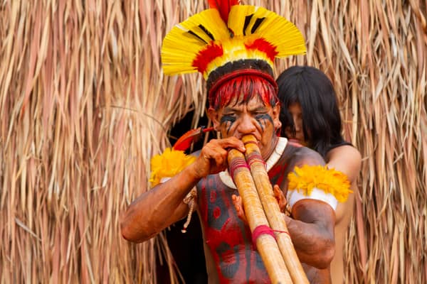 An elder playing a long ceremonial flute in the village