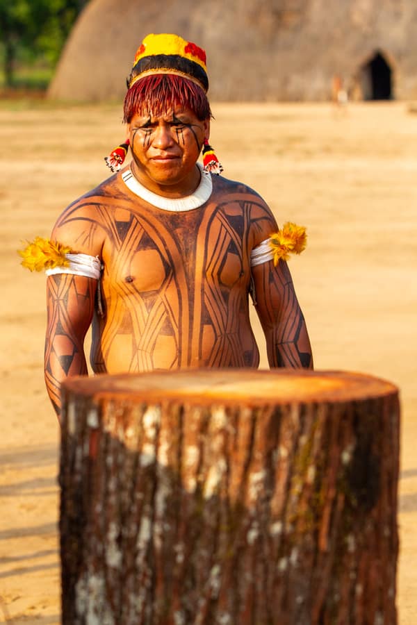 A man with intricate body paint in the village plaza
