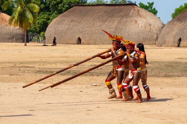 Men playing long flutes as they move through the village