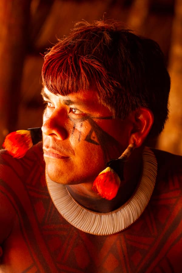 Portrait of a young man with face paint and feather ear ornaments