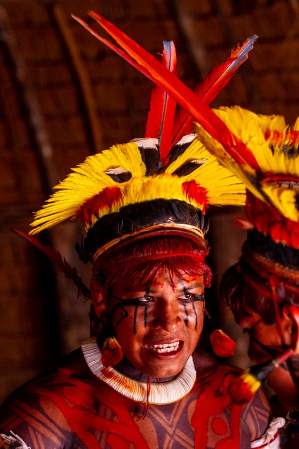 A man wearing a large feather headdress during a ceremony