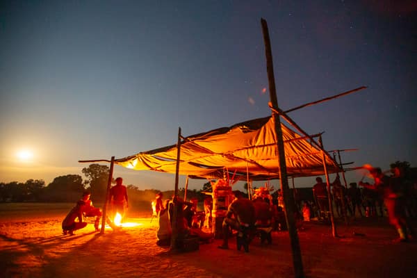 The community gathered under a shelter around a fire at night