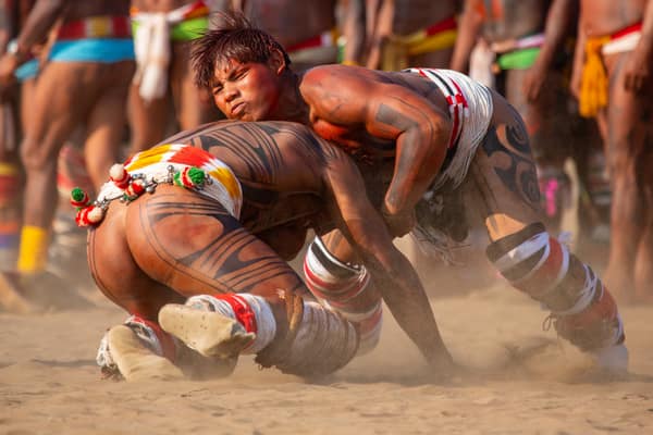Two young wrestlers grappling to the ground in the village plaza